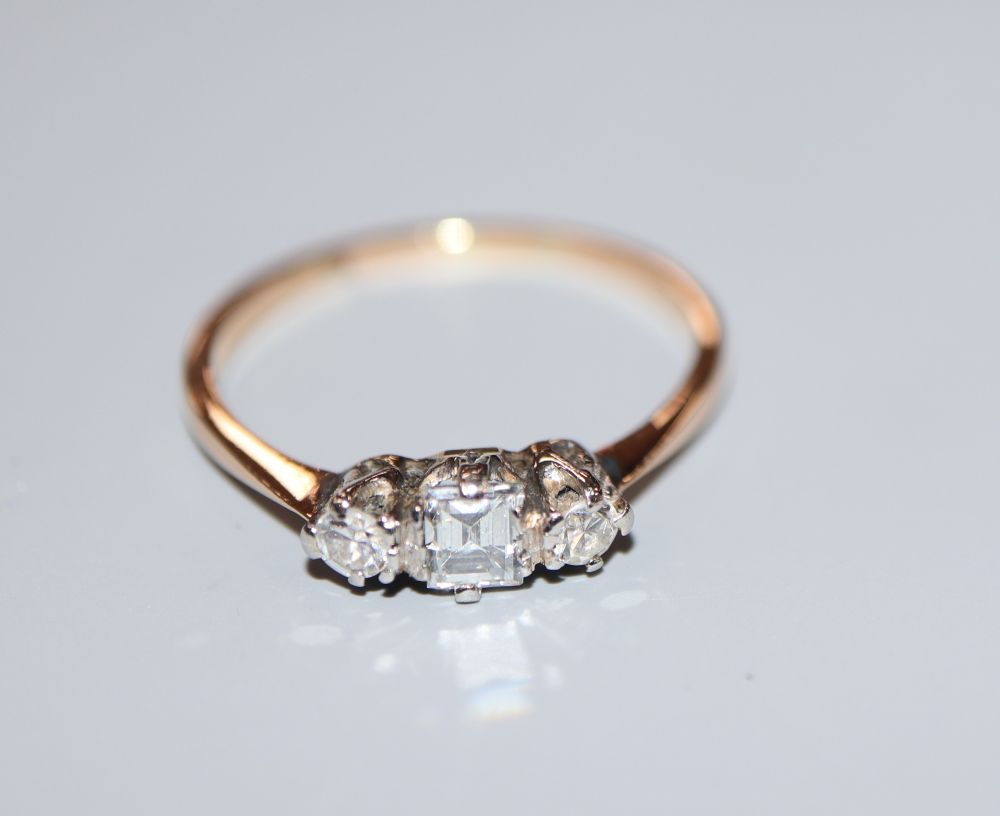 A yellow metal and three stone diamond ring, with central rectangular stone, size M, gross 1.6 grams.